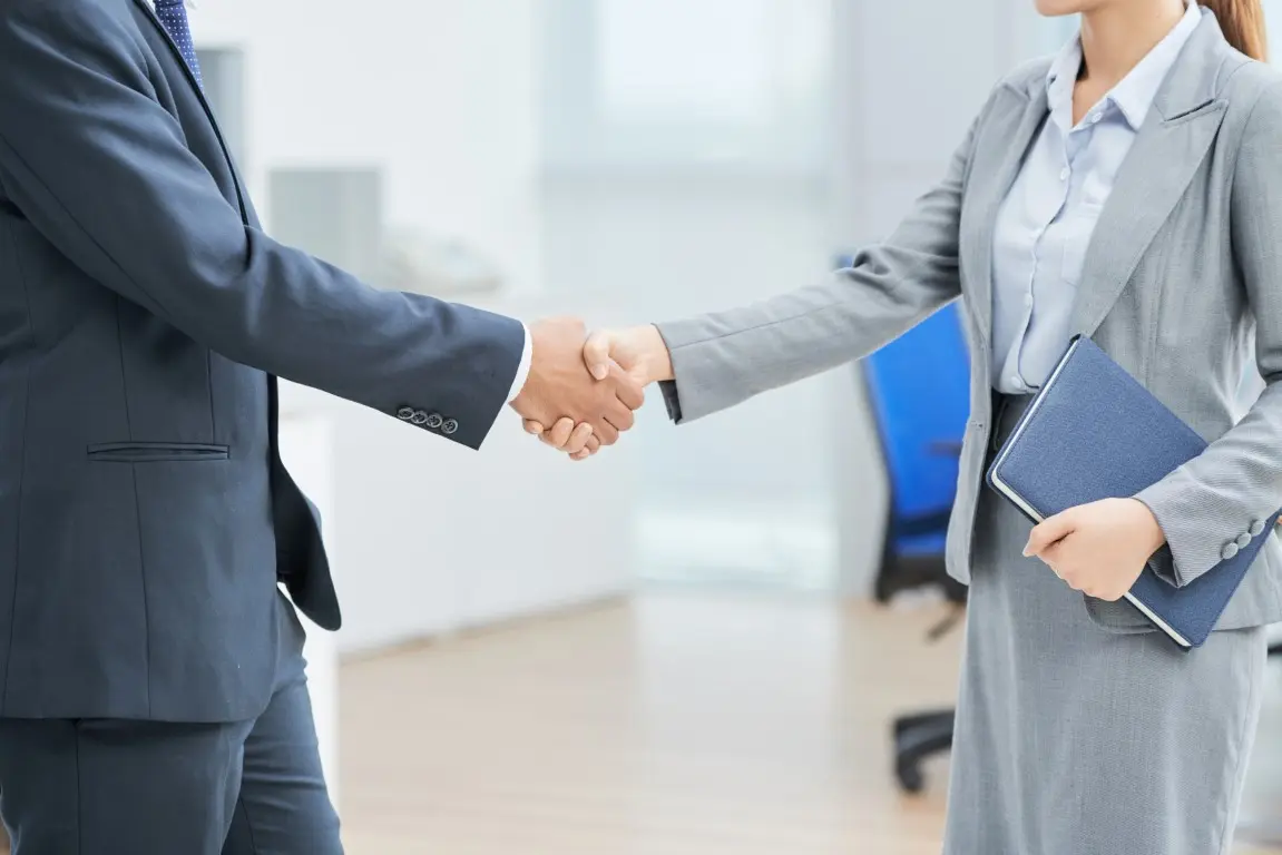 Two professionals shaking hands in an office.