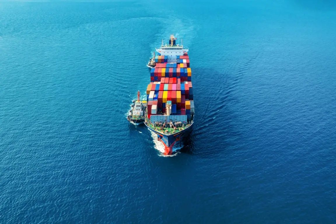 Aerial view of a container ship at sea with a smaller tug alongside.
