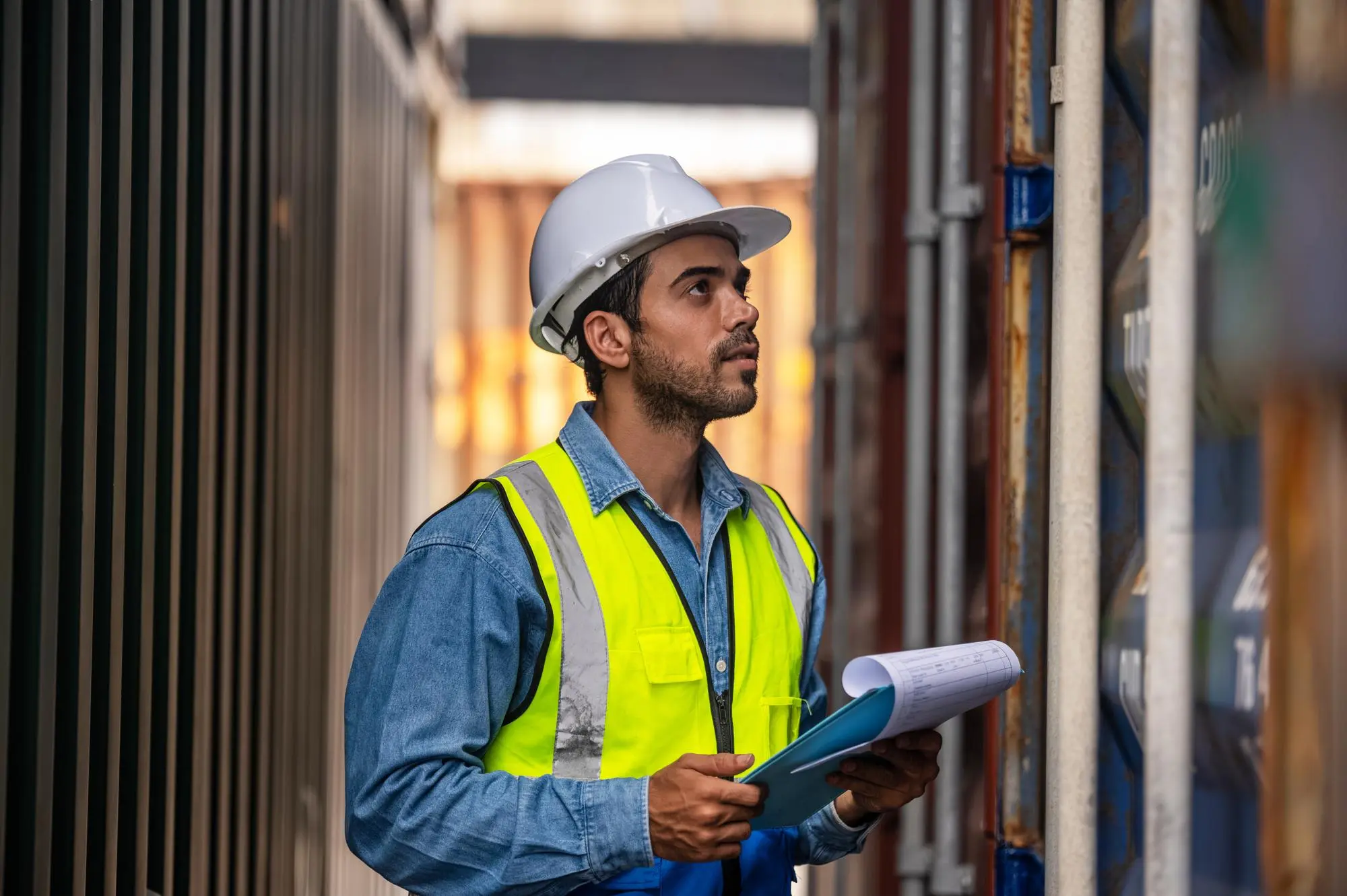 Port worker in a hard hat checking a consignment at a container terminal