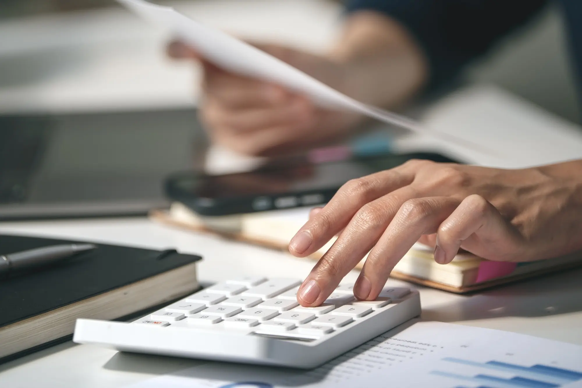 Accountant working through figures on a calculator beside financial documents